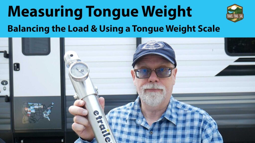 measuring tongue weight person standing in front of camper and holding tongue weight scale