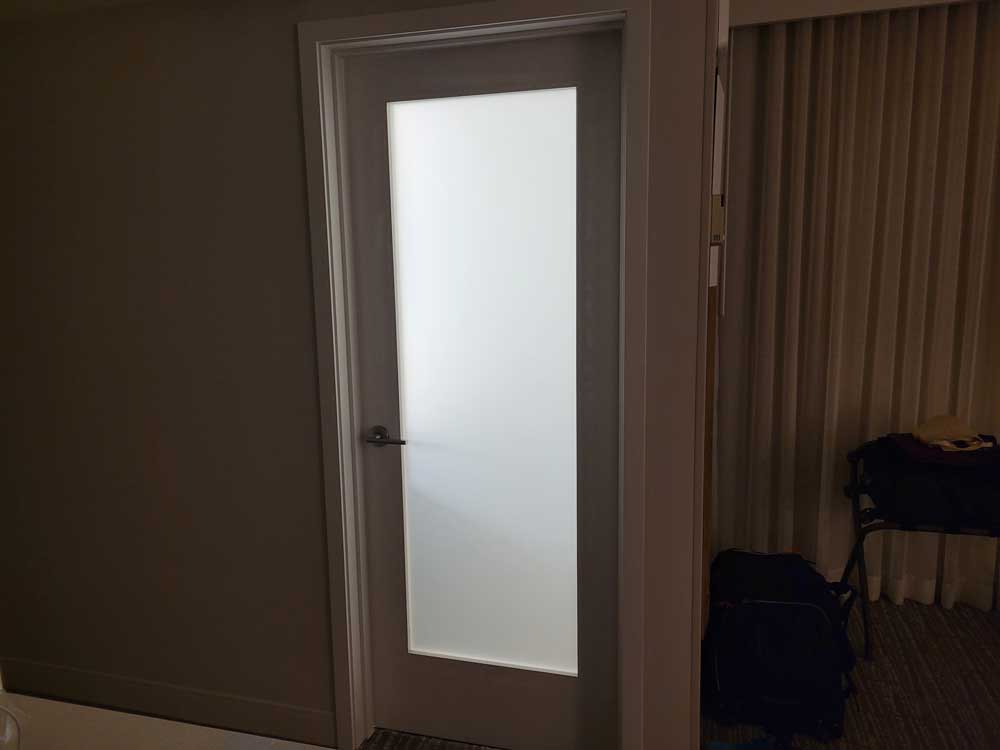 Brightly lit bathroom door with frosted glass at Waikiki Beach Marriott