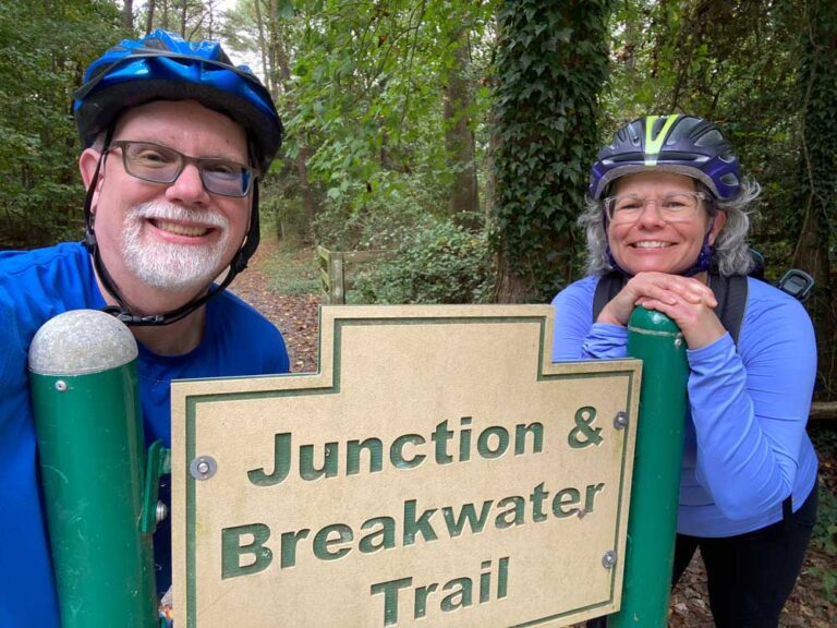 Erling and Judy standing next to a sign for the Junction and Breakwater bicycle trail