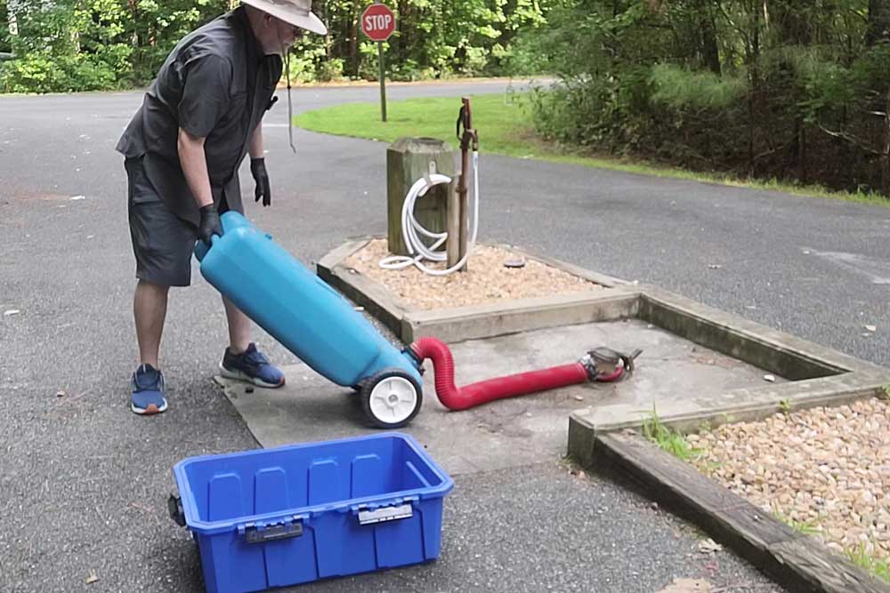 Man dumping gray water from RV tote tank at campground dump station